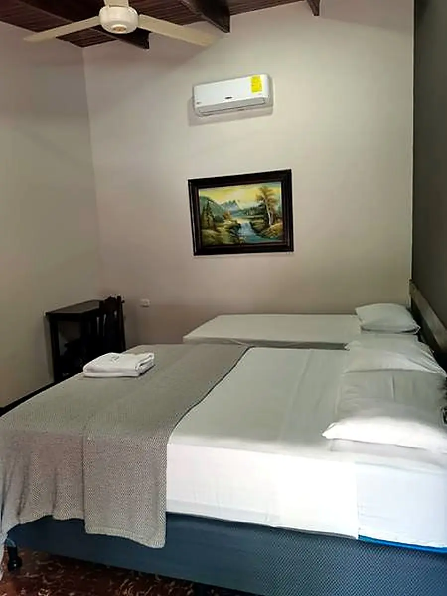 Habitación con una cama doble, una sencilla y aire acondicionado