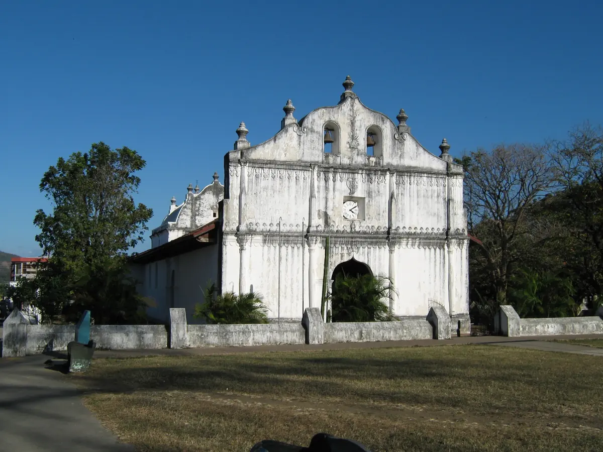 Fachada blanca de la iglesia colonial San Blas de Nicoya, con dos campanas y un reloj
